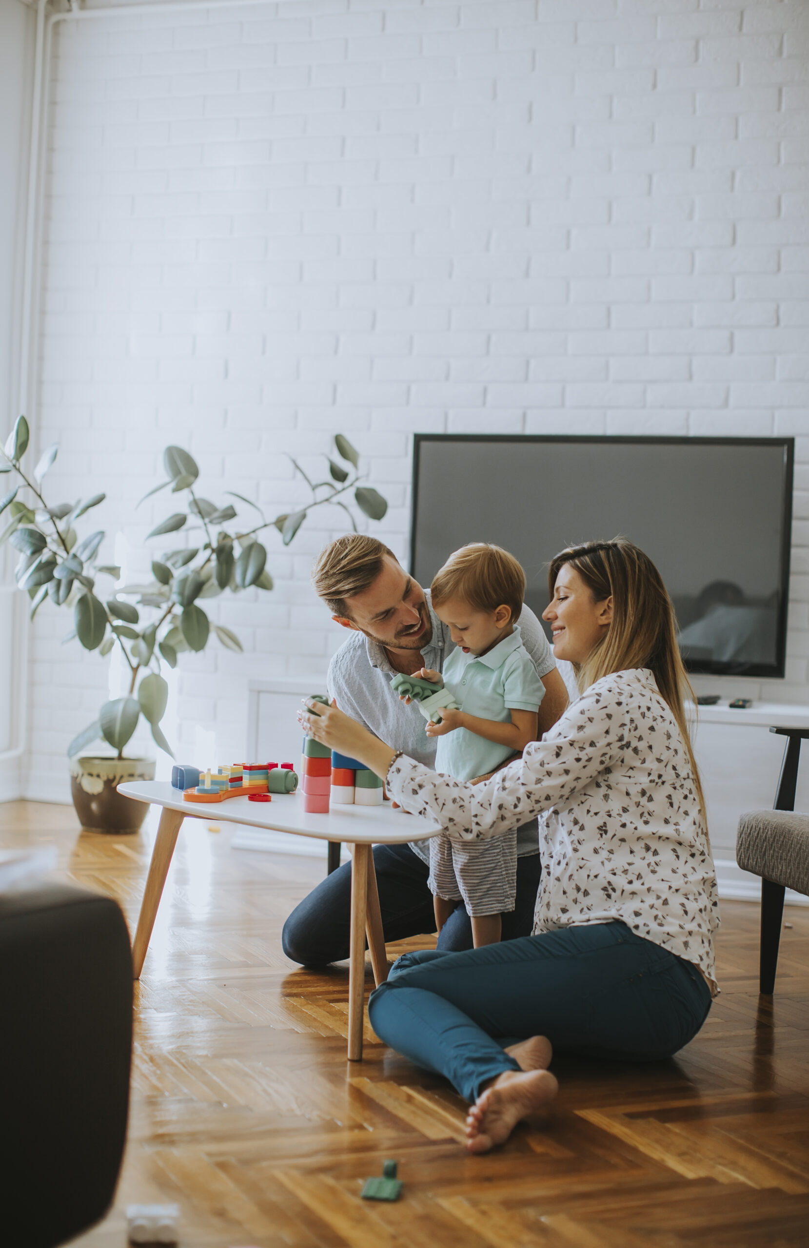 Little boy playing with toys in the living room with father and